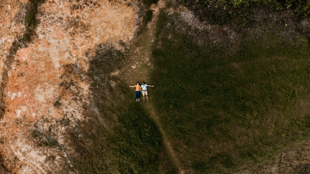 Aerial shot of a couple lying on grass in Hatton, Sri Lanka, showcasing nature's beauty.