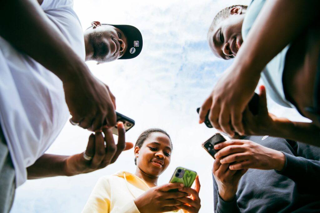 A diverse group of friends using smartphones together on a sunny day in Brussels.