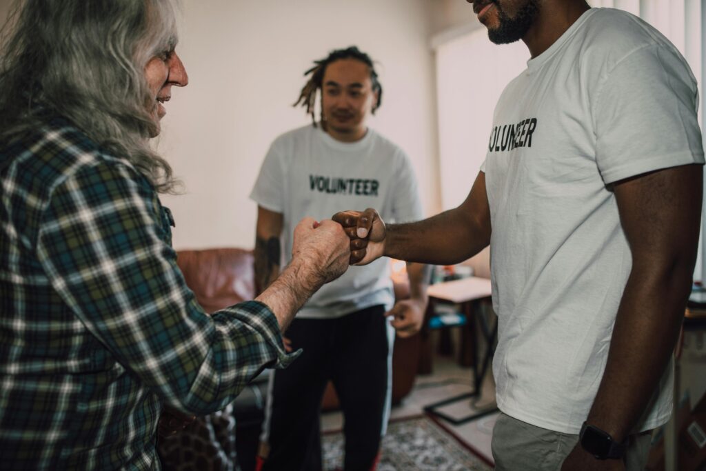 Three volunteers sharing a fist bump in a friendly indoor setting.