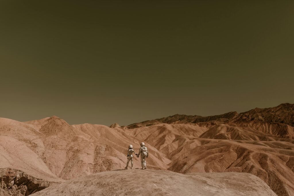 Astronauts holding hands, exploring a mars-like desert landscape under a clear sky.